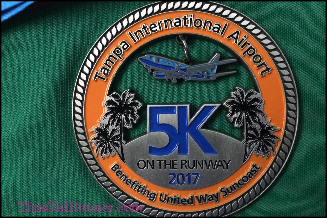 2017 medal for the TIA 5K on the Runway race has a moving plane.