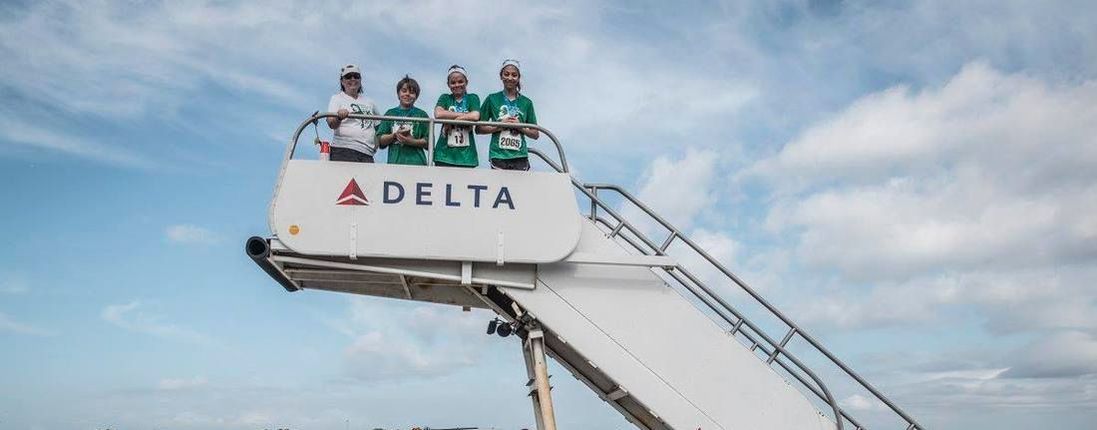 Runners pose on Delta airline steps at 5K on the Runway race in Tampa.