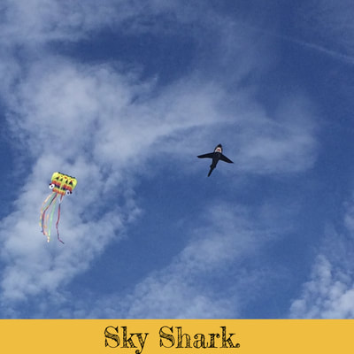 Shark and octopus kites in sky over the beach.